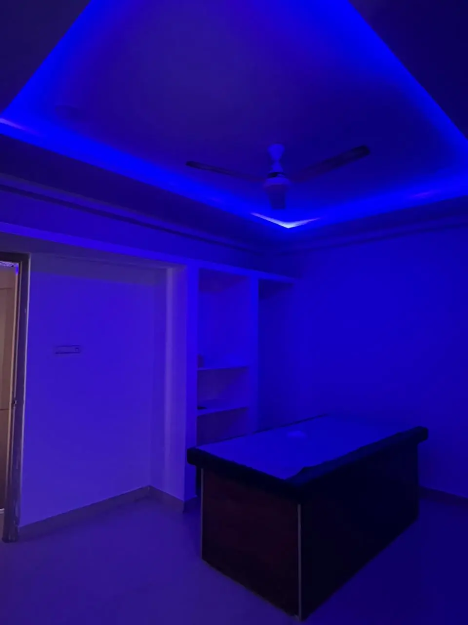 A second treatment room with a blue-lit ceiling and a made-up massage bed